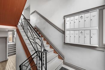 A staircase with a metal railing and a cabinet with drawers on the wall.